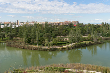 Beautiful green urban park. Public park with green grass fields, trees, waterways and pond. Parque de Cabecera, Valencia, Spain