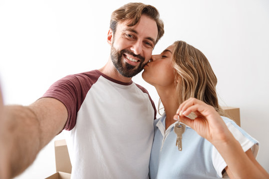 Photo of smiling couple taking selfie photo and holding keys - Powered by Adobe