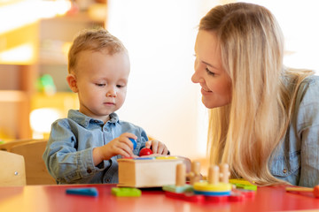 Fototapeta premium Woman and kid toddler playing logical toys at home