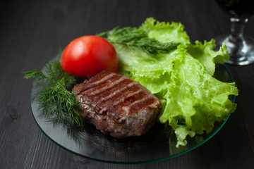 Grilled steak with vegetable salad and herbs. Concept for a tasty and healthy meal. Dark bakground