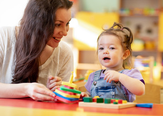 Fototapeta premium Woman and kid toddler playing logical toys at home