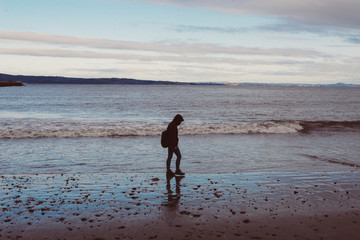 girl walking on an empty beach by the sea, durning winter