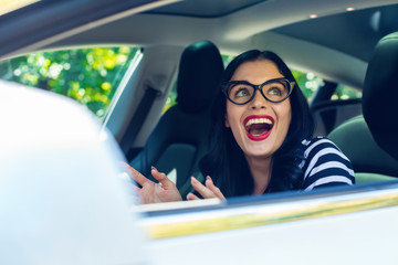 Woman in a self-driving autonomous electric vehicle with hands off the steering wheel