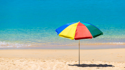 Pair of sun loungers and a beach umbrella on a deserted beach, Beach umbrella on a sunny day, sea in background.