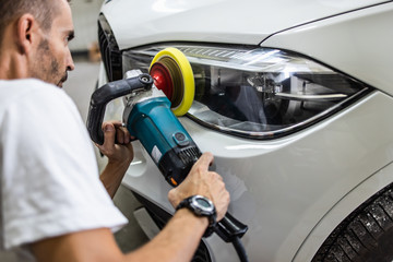 Car detailing - Hands with orbital polisher in auto repair shop. Selective focus.