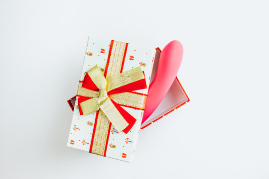 Christmas or New Year composition. Pink vibrator in a gift box on white background. Image for the festive season, for sales in sex shops. Top view. Copy space. Flat lay. Christmas minimal concept.