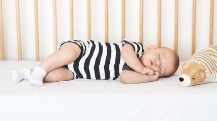 Adorable newborn baby sleeping on his side in crib