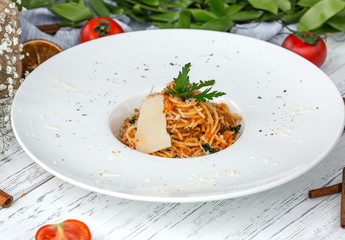 creamy carrot spaghetti with tomato, garnished with parsley and parmesan