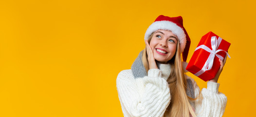 Dreamy girl with christmas gift looking at copy space