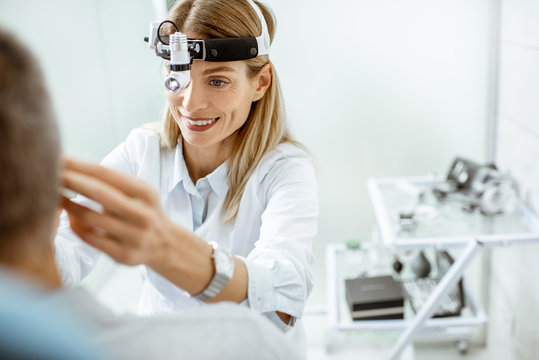 Portrait of a female confident otolaryngologist during a medical examination of a patient at the ENT office