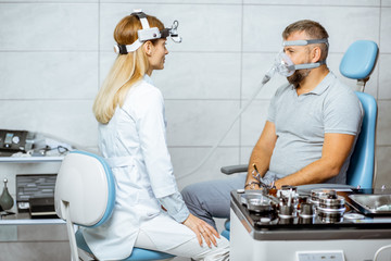 Adult man during a medical breathing treatment with respiratory mask against snoring sitting with doctor at the ENT office