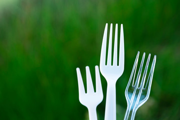white disposable white fork in garbage environmental pollution problem with green nature background