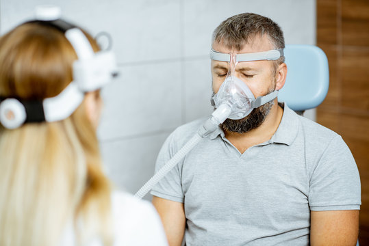 Adult Man During A Medical Breathing Treatment With Respiratory Mask Against Snoring Sitting With Doctor At The ENT Office