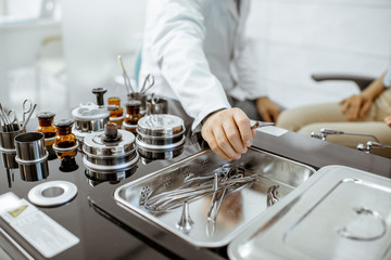 Otolaryngologist taking medical tweezers from the ENT workstation during a procedure, close-up view