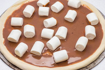 Pizza. Top view. Raw dough. Sweet pieces of pizza with murshmello and nutella. Black and white backgrond. Taste piece. 