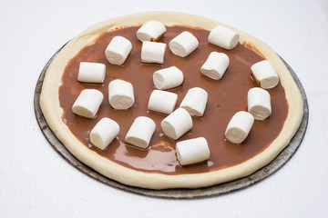 Pizza. Raw dough. Sweet pieces of pizza with murshmello and nutella. Taste piece.   Top view. Black and white backgrond. 