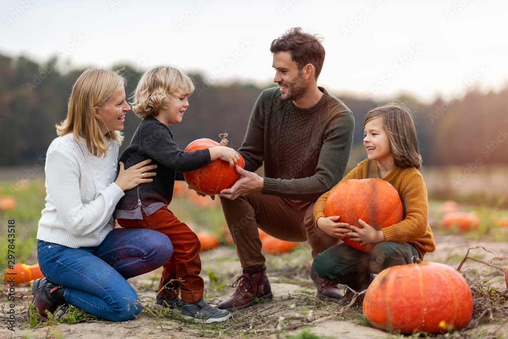 Wall mural Happy young family in pumpkin patch field