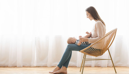 Mother sitting in wicker chair holding newborn baby on lap