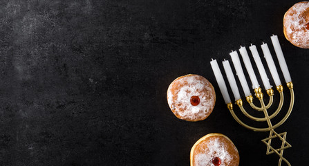 Jewish Hanukkah menorah and sufganiyot donuts on black background. Panorama view
