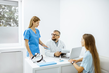 Young patient at an appointment with otolaryngologists, sitting during the consultation in the bright ENT office interior