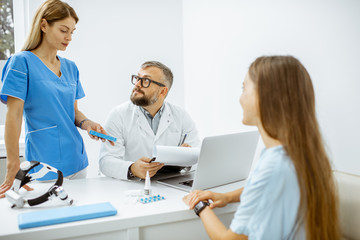 Young patient at an appointment with otolaryngologists, sitting during the consultation in the bright ENT office interior