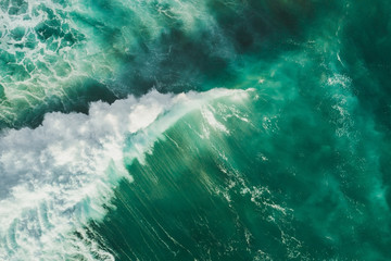 Fototapeta na wymiar Aerial wave background. Drone shot directly from above, green turquoise color, huge waves. Empty space