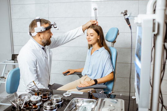 Senior otolaryngologist examining ears with ENT tuning fork for a young patient in the medical office. Hearing test with tuning fork concept