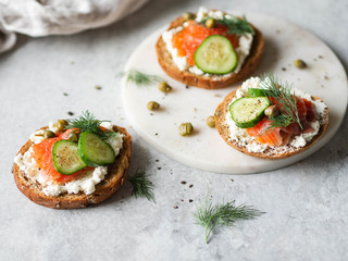 Several sandwiches on rye bread with cream cheese, salmon, fresh cucumber and spices.