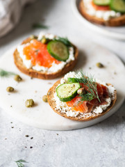 Several sandwiches on rye bread with cream cheese, salmon, fresh cucumber and spices.