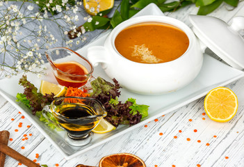 lentil soup in ceramic serving ware served with fresh salad and sauces