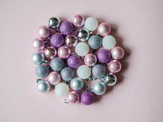Various color christmas balls in the shape of a circle on a pink background