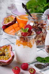 Natural yogurt, granola and mashed passion fruit and mango layered in a glass jar. Breakfast idea