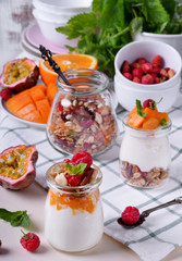 Natural yogurt, granola and mashed passion fruit and mango layered in a glass jar. Breakfast idea