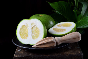 Sweetie cut into halves on a stone plate on the edge of the wooden table against black background