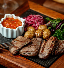 marinated beef steak pieces served with onion, fresh herbs and tomato sauce