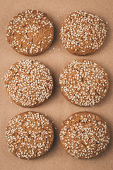 Oat cookie with sesame seeds on craft paper. Brown background. Homemade baking.
