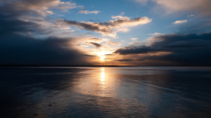 Stunningly beautiful sunrise, taken on a cloudy morning from Salthill beach near Galway, Ireland. Showing the calm water of Galway Bay and Mutton Island in the distance.