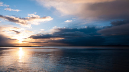 Fototapeta na wymiar Stunningly beautiful sunrise, taken on a cloudy morning from Salthill beach near Galway, Ireland. Showing the calm water of Galway Bay and Mutton Island in the distance.