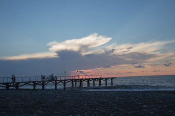 Obraz premium over Batumi beach Jetty, as powerful waves roll in, and a very colorful sky is reflected on the beach. sunset on the city embankment