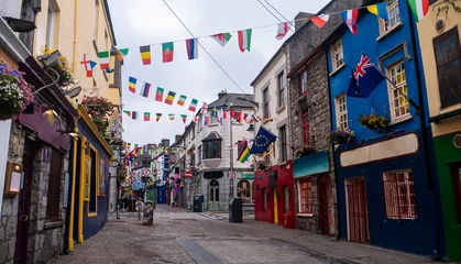 Gordijnen Uitzicht op de hoofdstraat in Galway City met de felgekleurde gebouwen en geplaveide straten op een bewolkte dag © Michaella