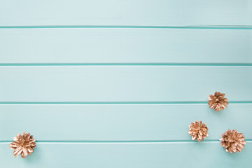Golden cones on wooden turquoise table, space for text, copy space. Empty lay surface, design Christmas background. 