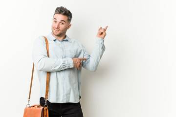 Young handsome business man smiling cheerfully pointing with forefinger away.