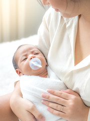 A beautiful Asian woman puts her newborn baby on her body happily and with love