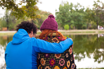 Couple hugging on a river bank; back view, selective focus.