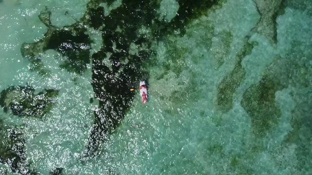Very high view of a tourist female paddling on green water surface on sunlight in Pulau Bruit, Malaysia