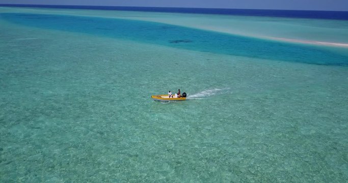 Top view over a yellow boat sailing around emerald water near lagoon of Dos Hermanos island, Philippines
