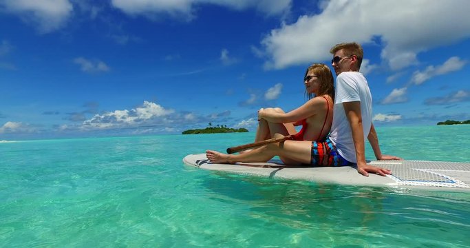 sitting couple in paddle board in philippine sea, parallax shot