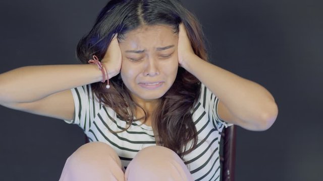 Close up of young afraid asian girl sitting alone in room and screaming