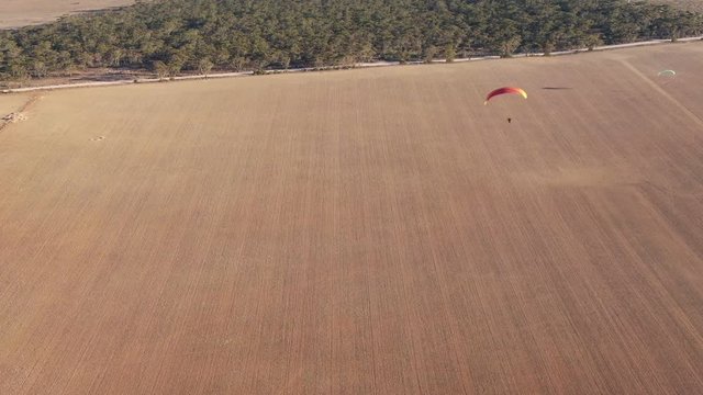 Nice aerial drone view of paramotor gliding and flying above the wide Granite field of South Australia