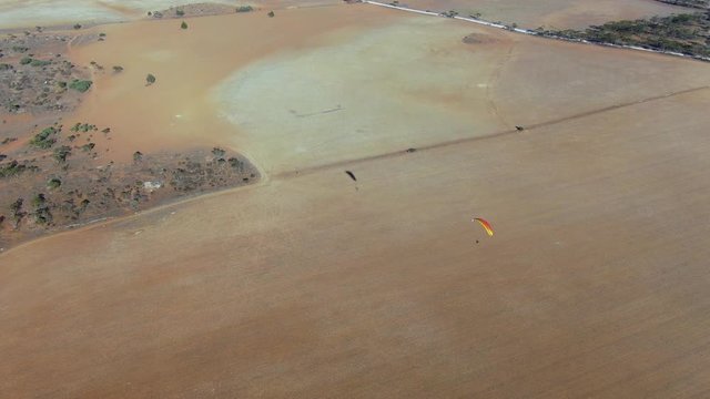 Nice drone aerial view of powered paragliding extreme sport enjoying flying in the air above the wide Granite field